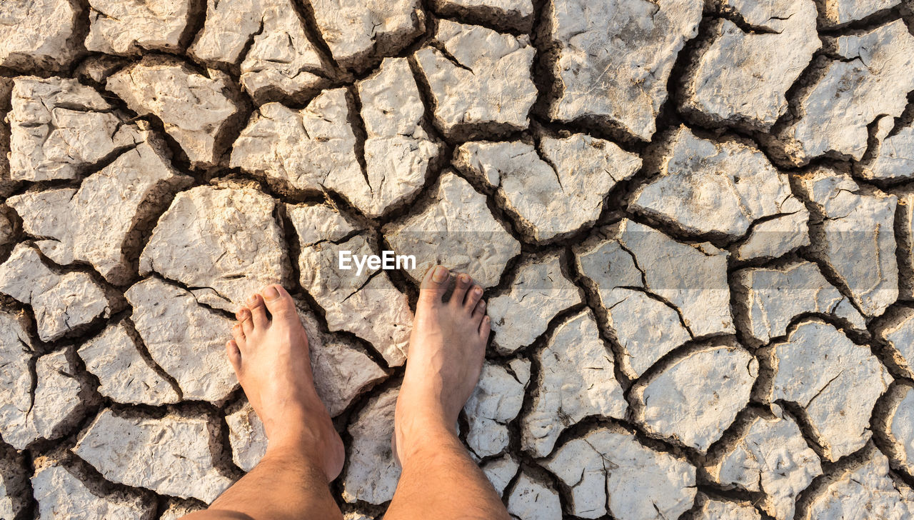 Low section of person standing on drought land