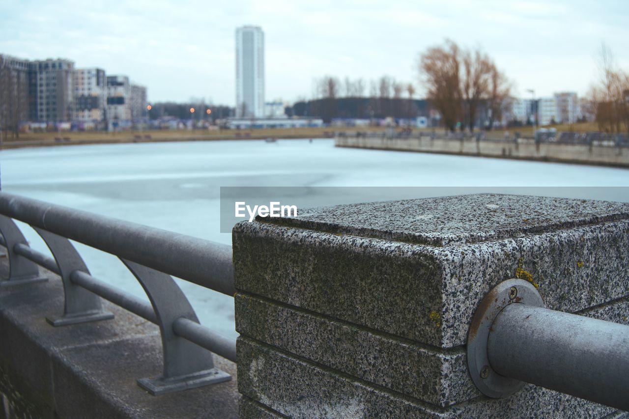 Close-up of hand by railing against river in city