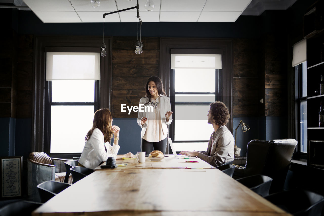 Colleagues looking at businesswoman explaining in office