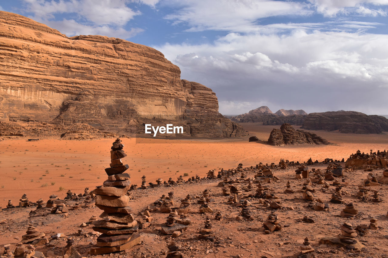 Red rock formations on wadi rum landscape against cloudy sky