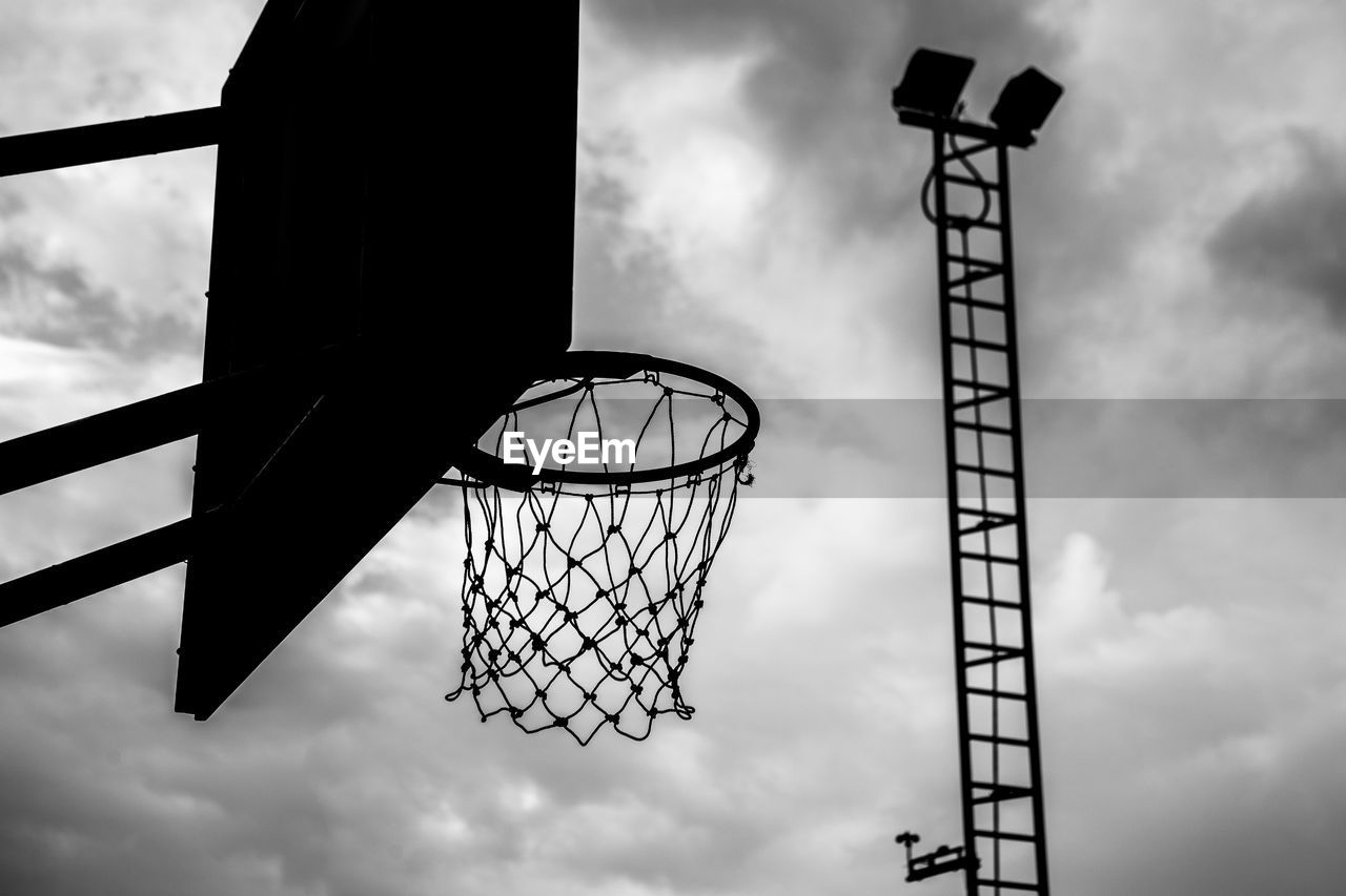 LOW ANGLE VIEW OF BASKETBALL HOOP AGAINST CLOUDY SKY