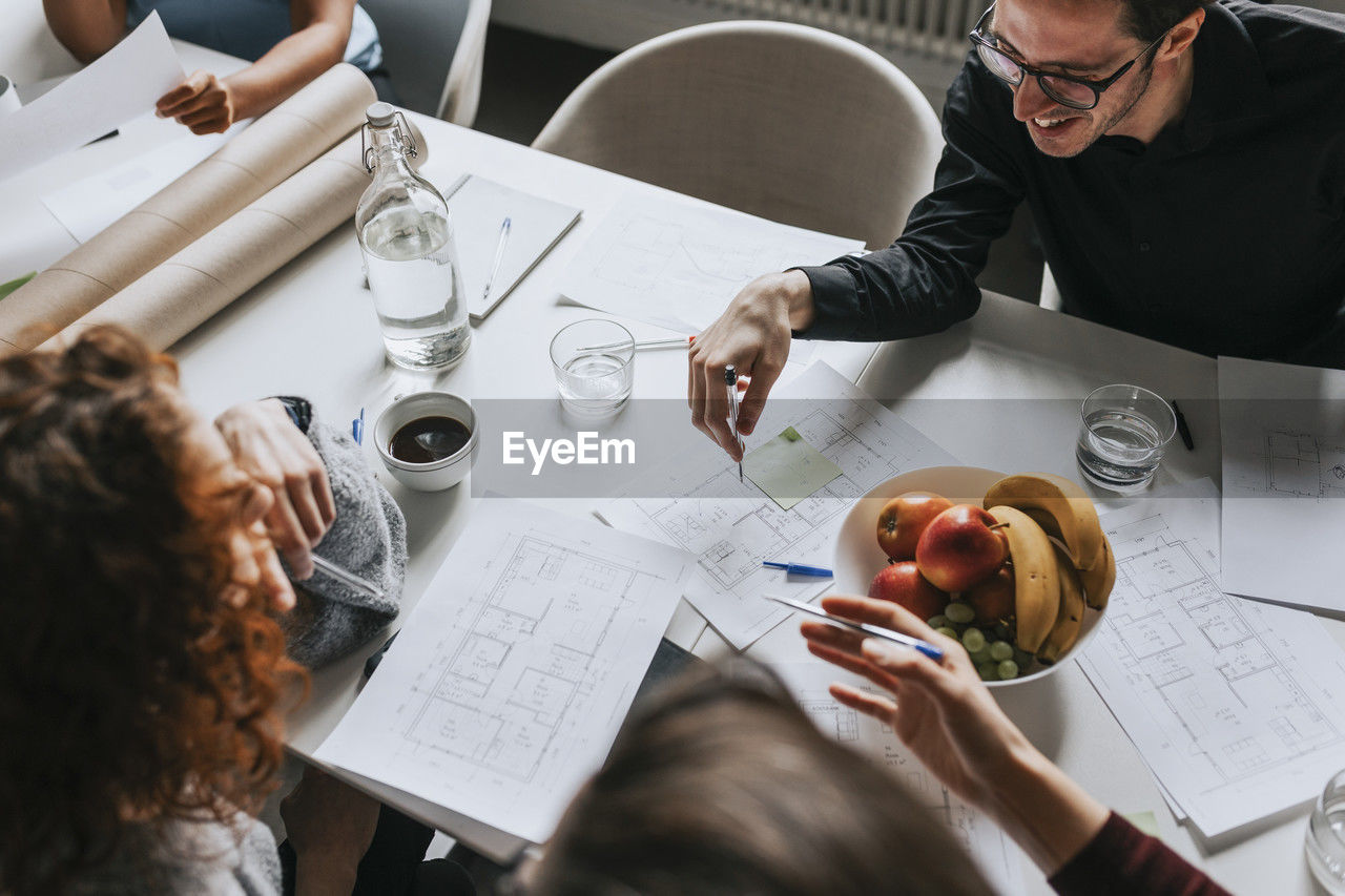 High angle view of business people planning strategy at desk with fruits at office