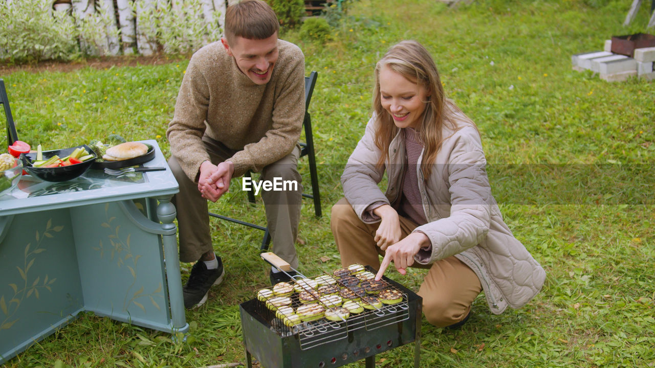 Couple preparing food while sitting at yard