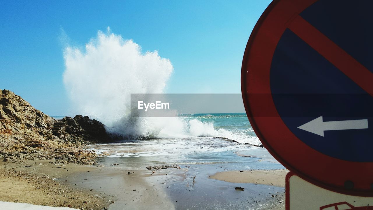 Waves splashing on rocks against sky at beach