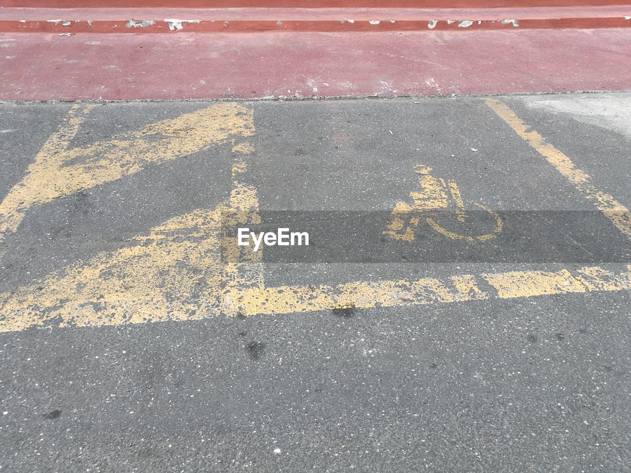 HIGH ANGLE VIEW OF ARROW SYMBOL ON ASPHALT ROAD