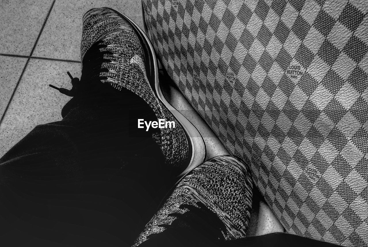 black, human leg, low section, one person, black and white, shoe, lifestyles, personal perspective, limb, human limb, monochrome photography, adult, high angle view, monochrome, women, pattern, indoors, white, footwear, human foot, leisure activity, sitting, relaxation, fashion, flooring, casual clothing, clothing, standing, men