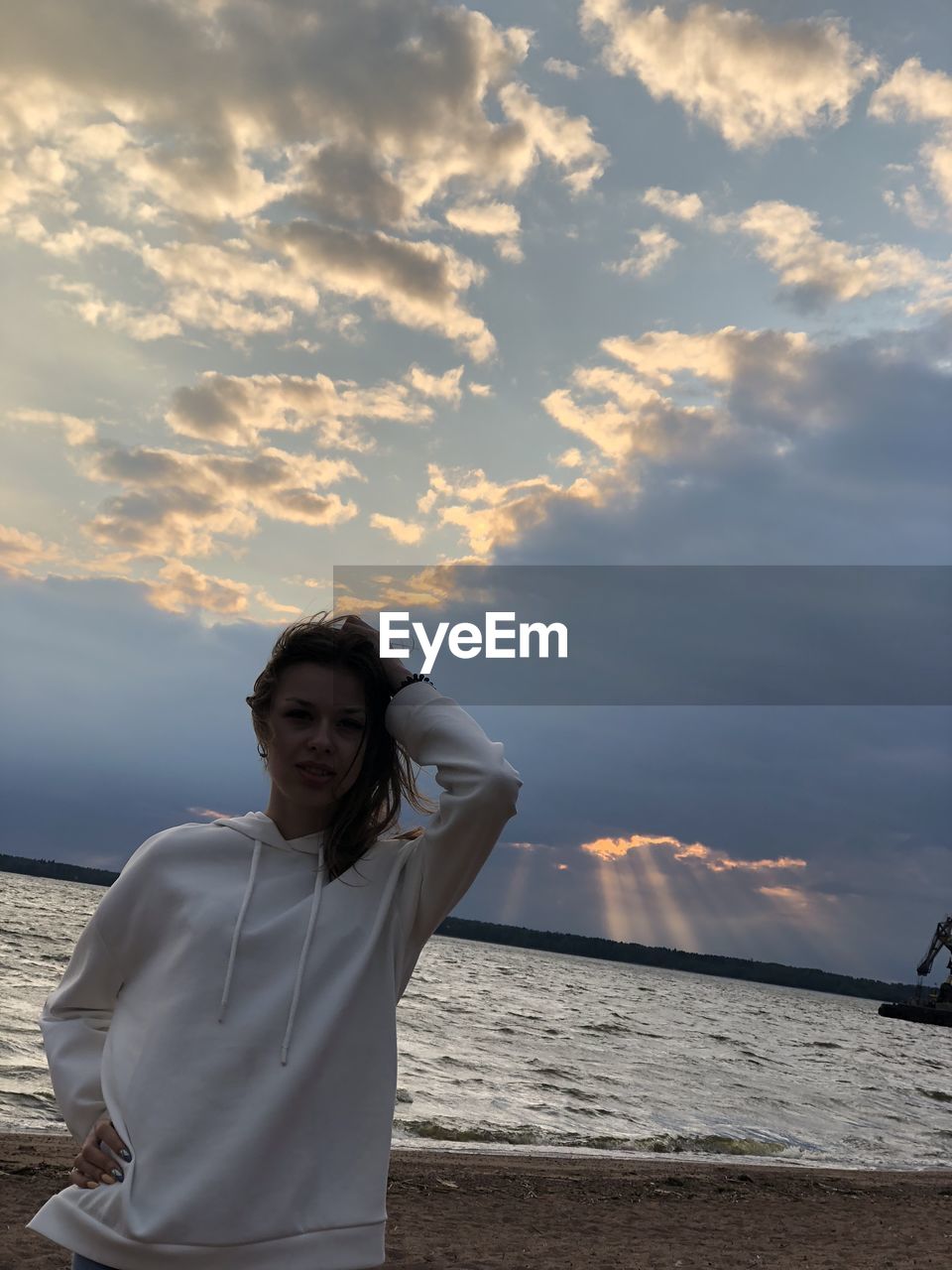 Woman standing on beach against sky during sunset