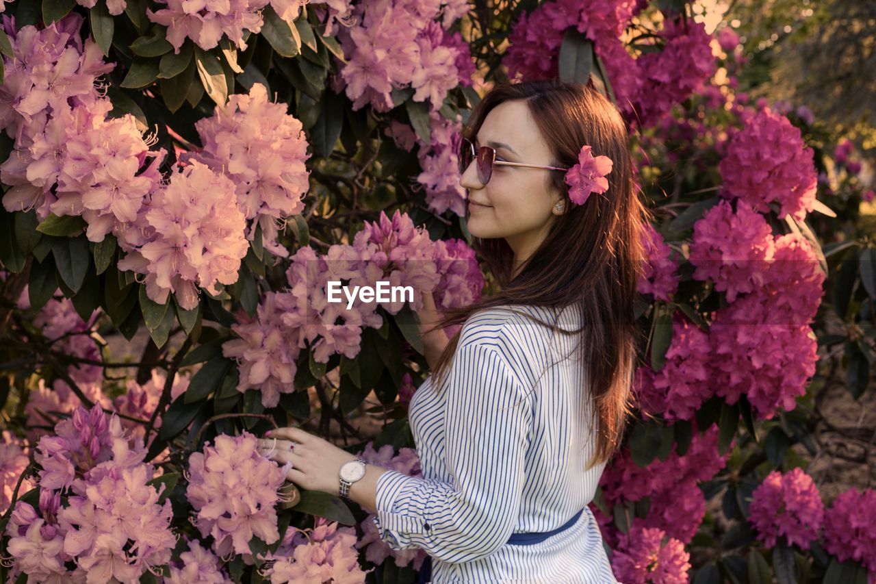 Woman in sunglasses standing by pink flowering plants