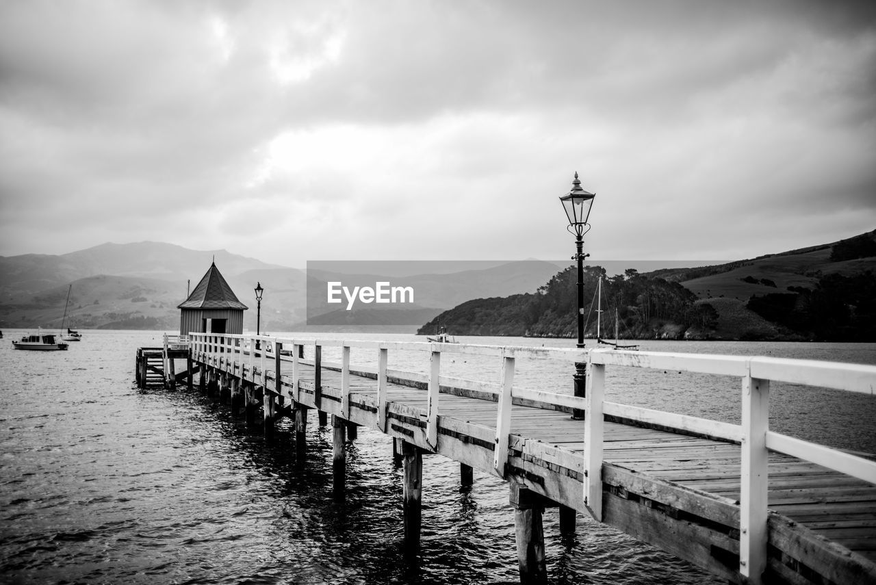 Pier on sea against cloudy sky