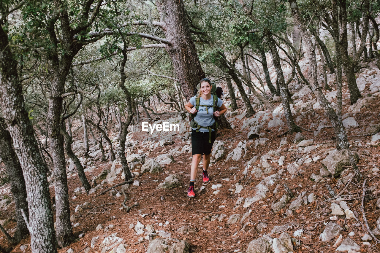 Portrait of woman standing against tree trunk in forest