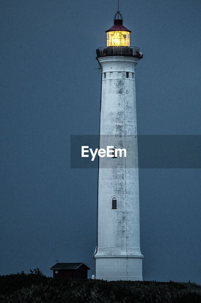 lighthouse by sea against clear sky
