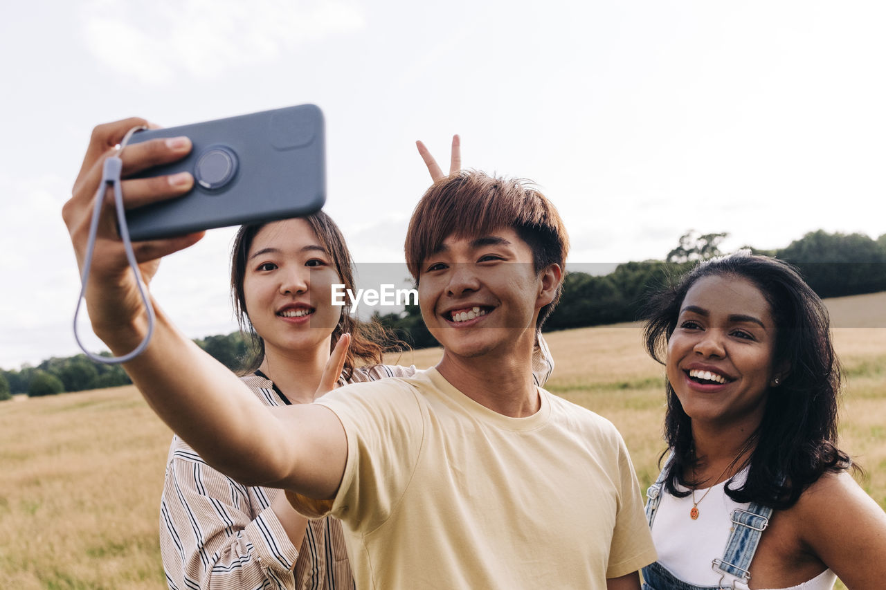 Smiling friends taking selfie through mobile phone at park