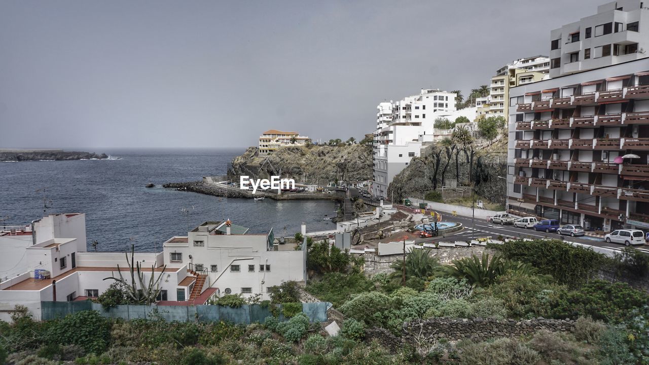 Buildings by sea against sky in city