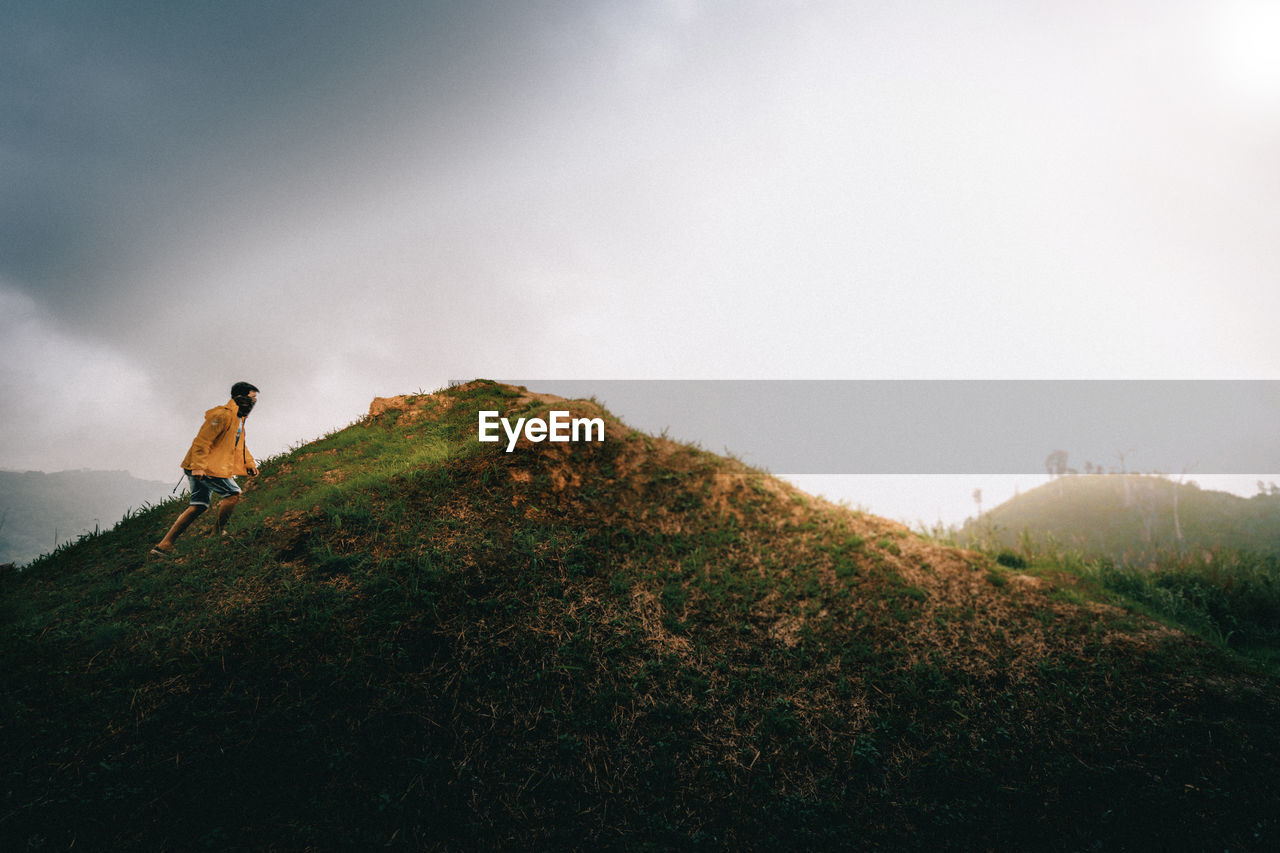 Man climbing on mountain against sky