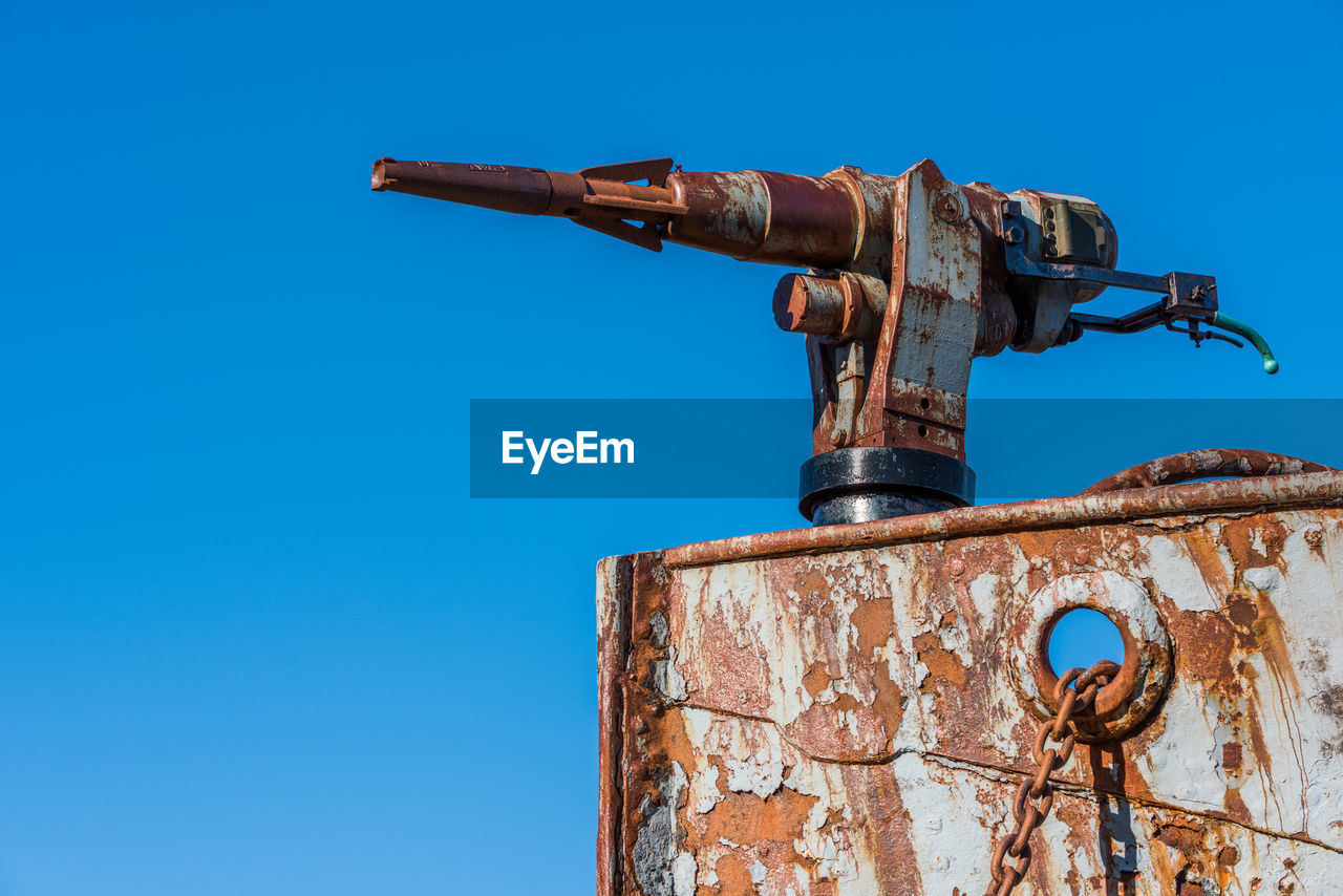 Low angle view of rusty metal against clear blue sky