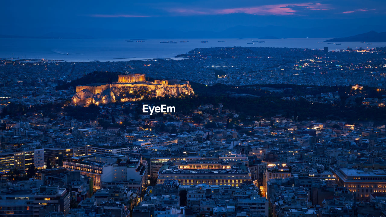 Illuminated cityscape against sky during sunset