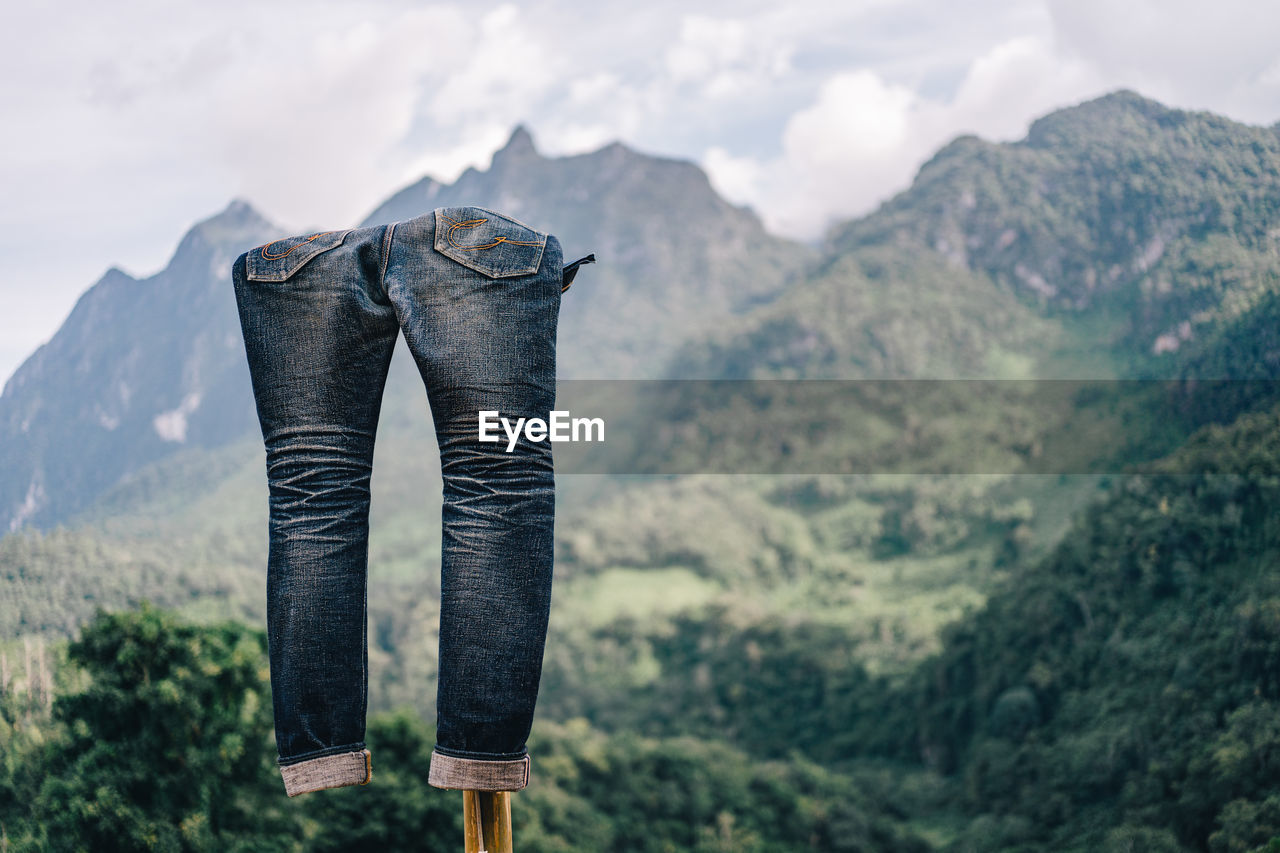 LOW ANGLE VIEW OF PERSON STANDING ON MOUNTAIN