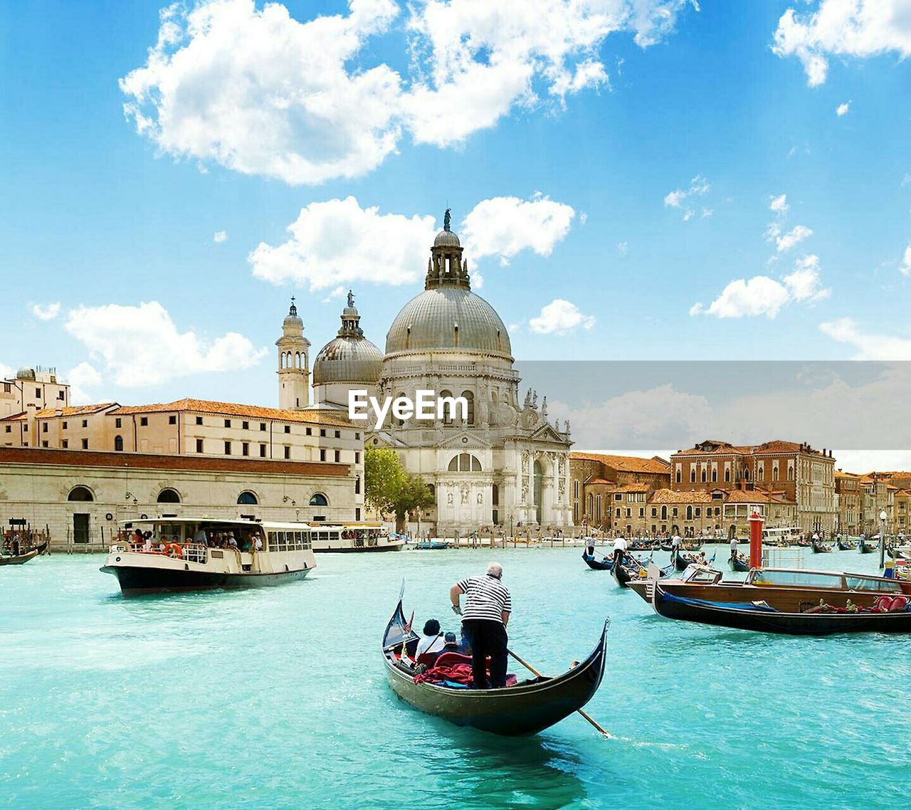 Ferry with gondolas sailing in grand canal by santa maria della salute against sky