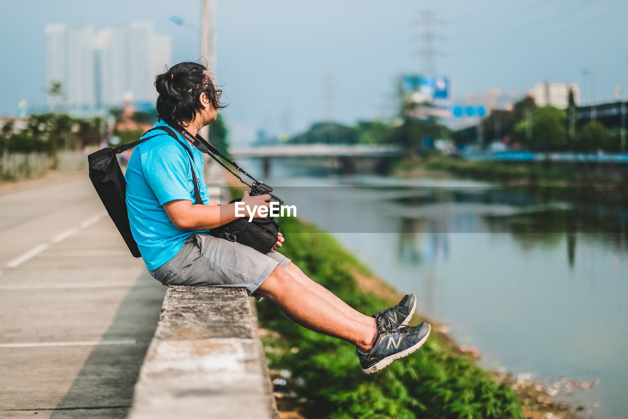 MAN PHOTOGRAPHING WITH UMBRELLA ON LAKE