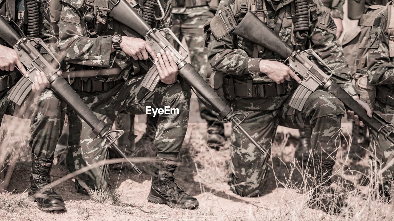 Low section of army soldiers with rifle on field