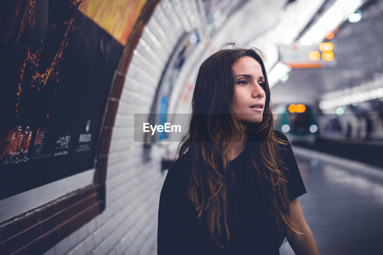 Thoughtful young woman sitting at railroad station platform