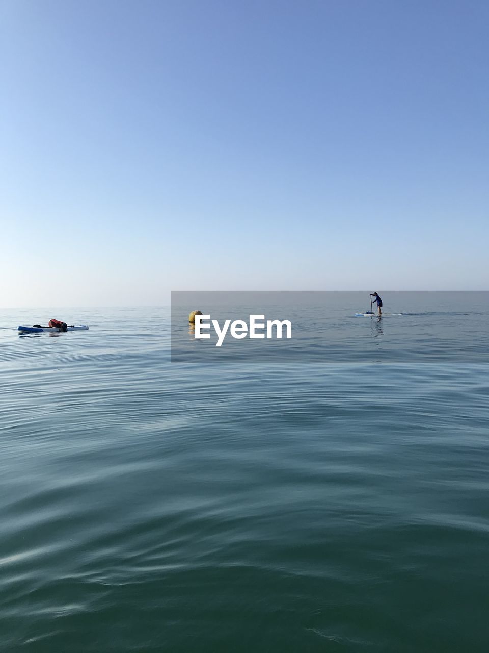 PEOPLE SWIMMING IN SEA AGAINST CLEAR BLUE SKY