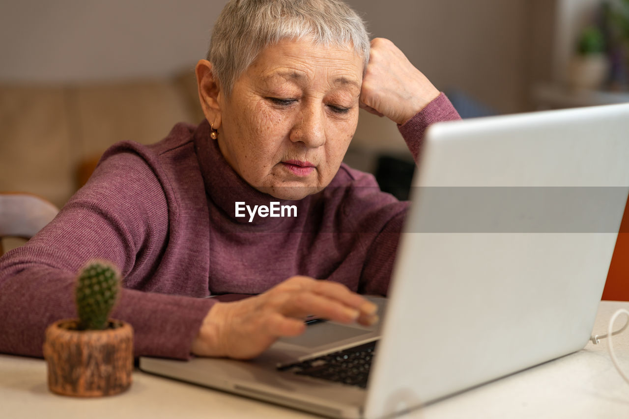 A woman sitting in front of a laptop communicates online through social networks.