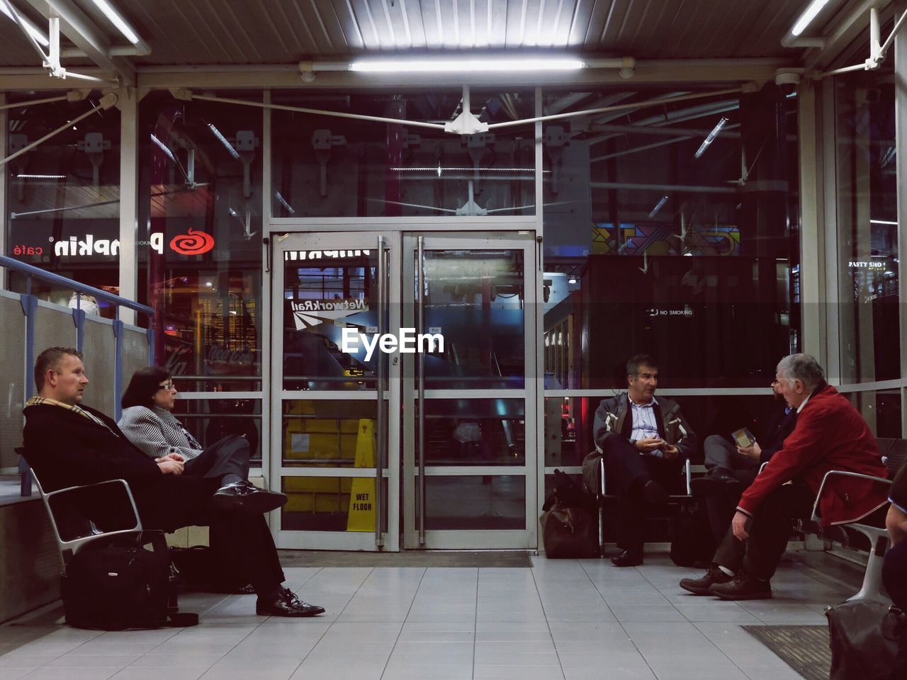 PEOPLE STANDING AT ILLUMINATED UNDERGROUND STATION