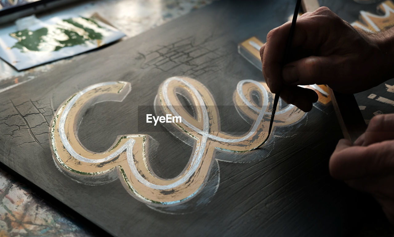 Cropped image of painter painting on wood