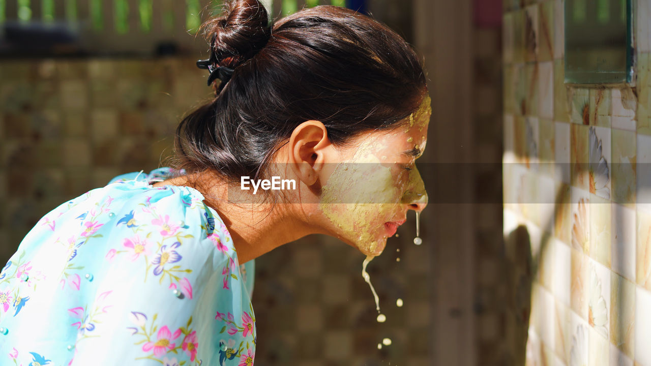 Beautiful woman is washing facial mask in bathroom after applying face mask.