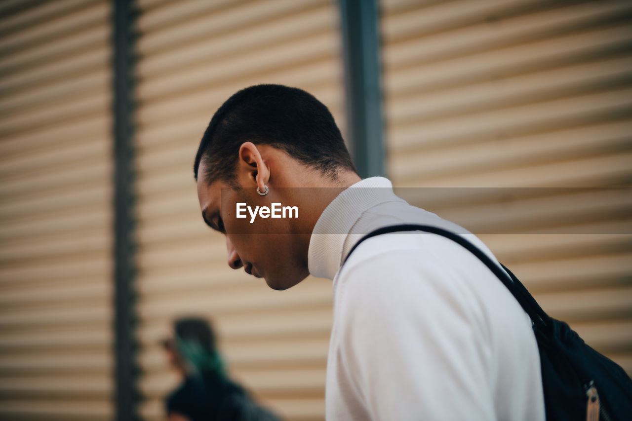 Close-up of young man looking down in city