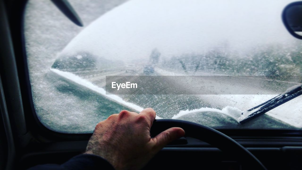 Cropped image of man driving car during winter