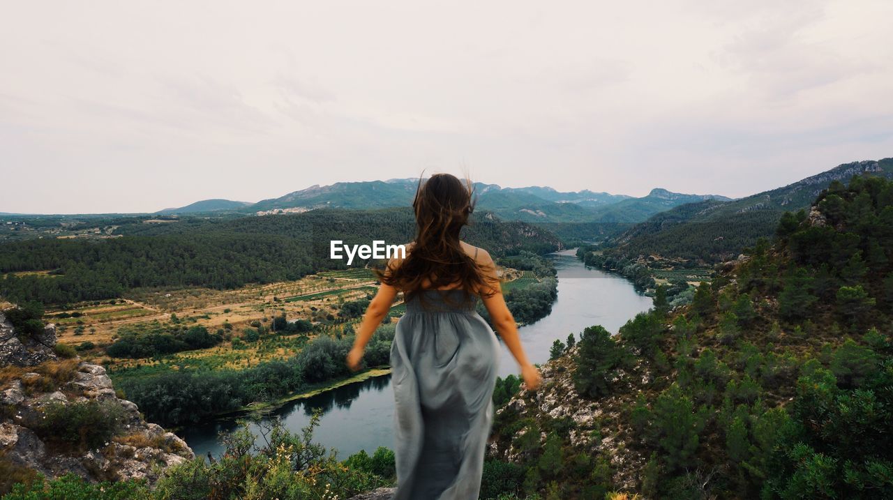 Rear view of man standing on landscape against mountain range