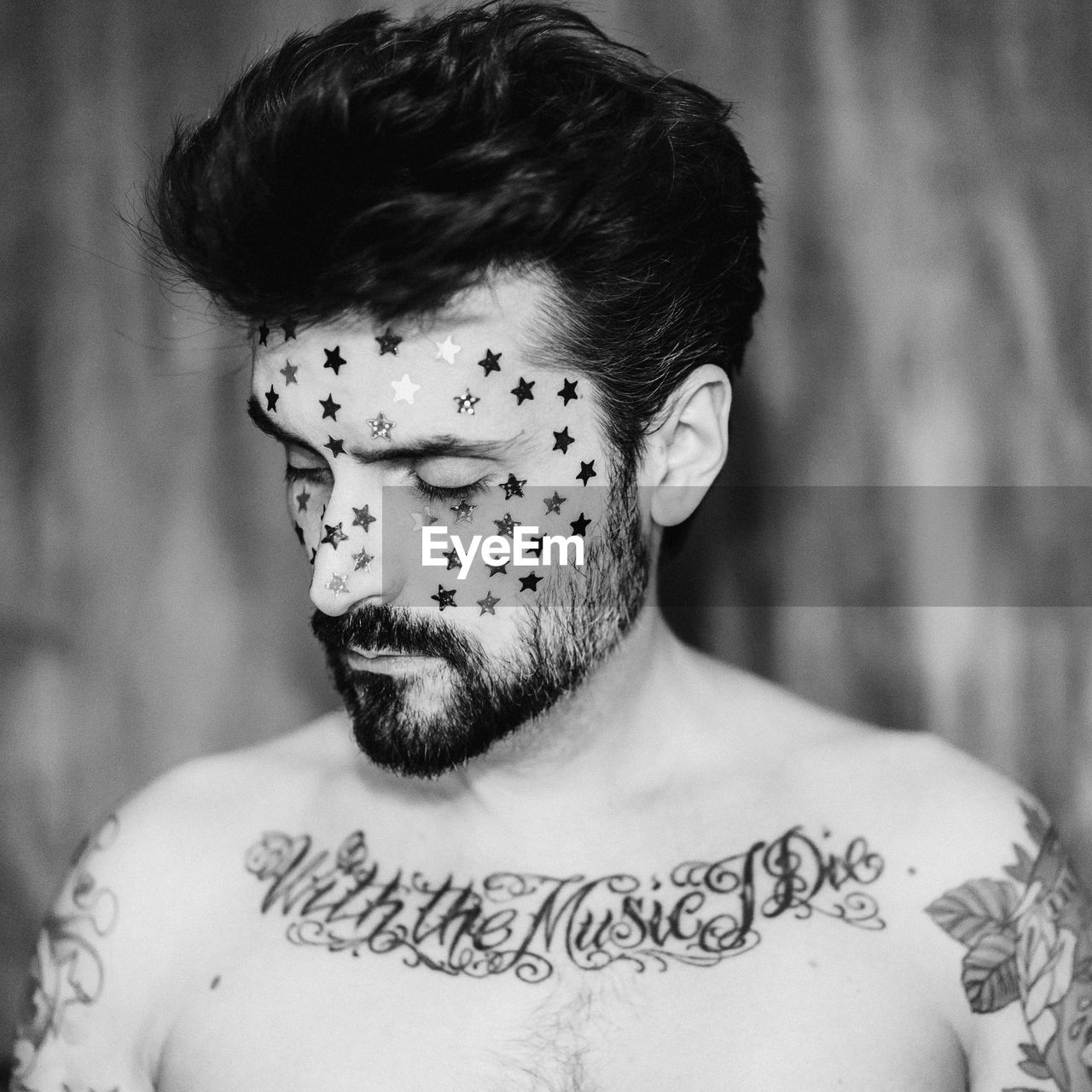 Shirtless man with tattoo and stars on face