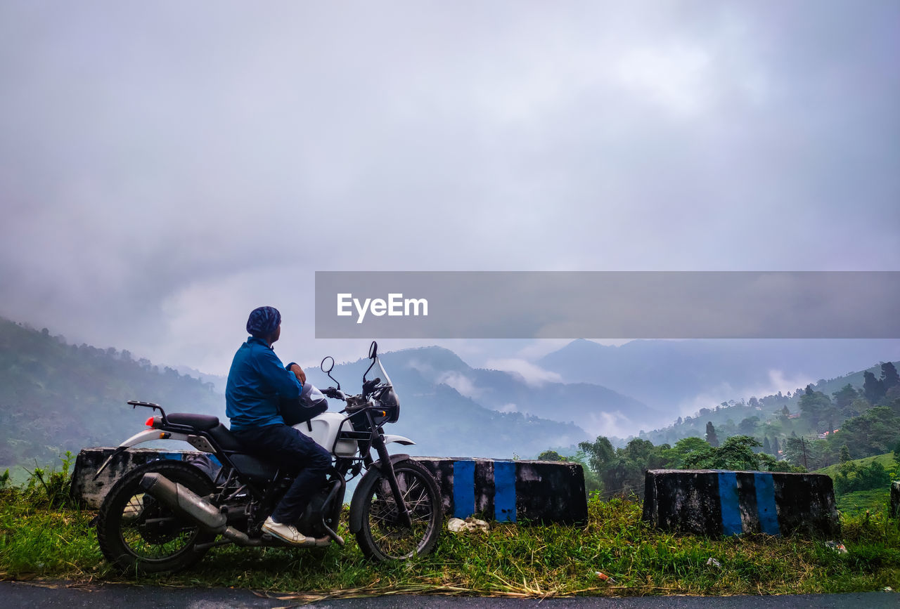 Young man motorcycle rider enjoy the beautiful mountain view at morning from flat angle