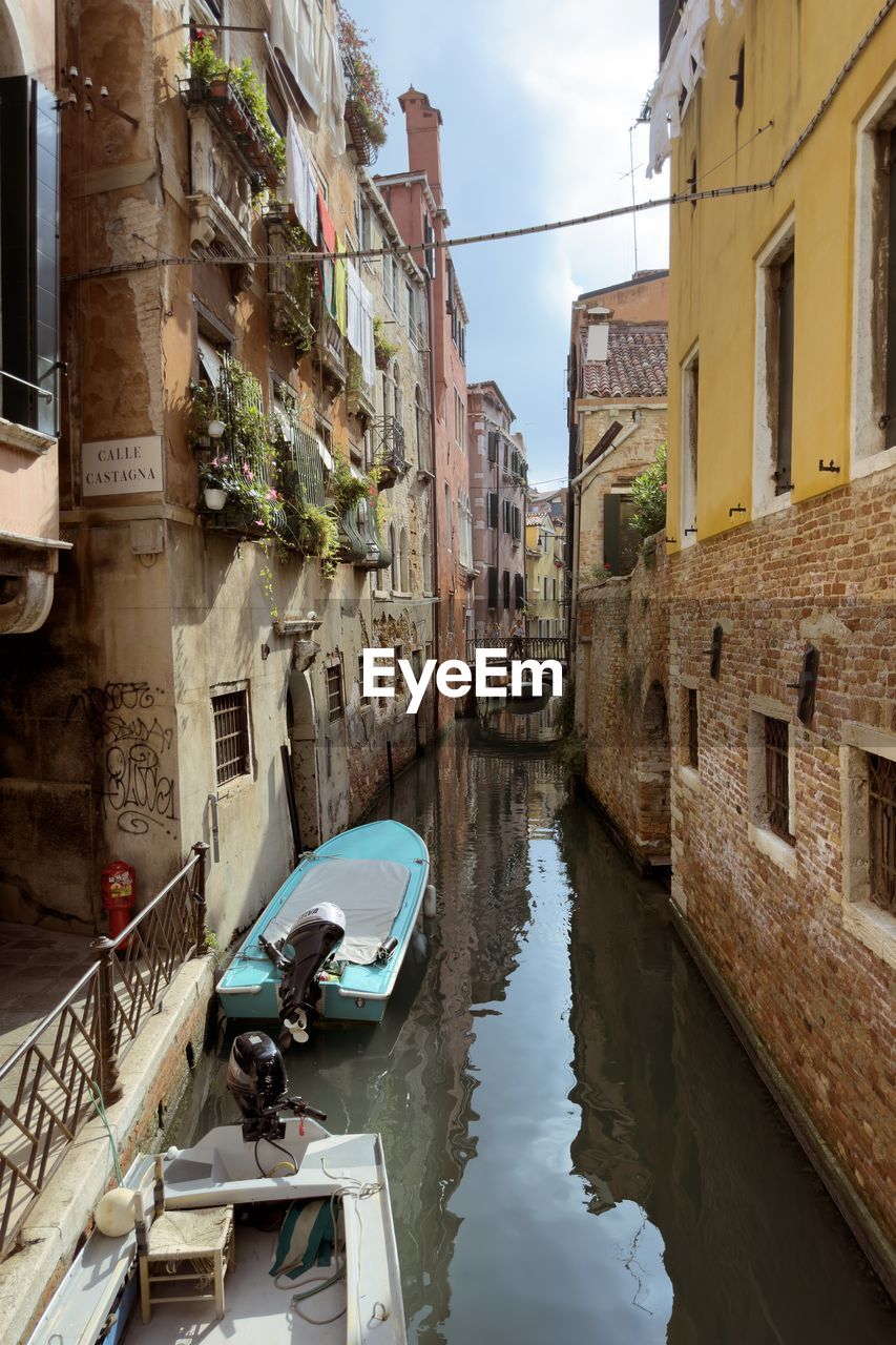 boats in canal amidst buildings