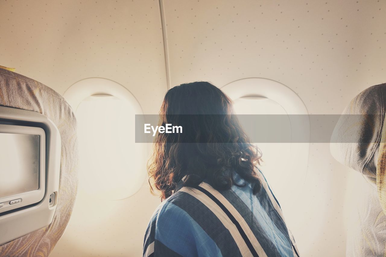 Rear view of woman by window in airplane