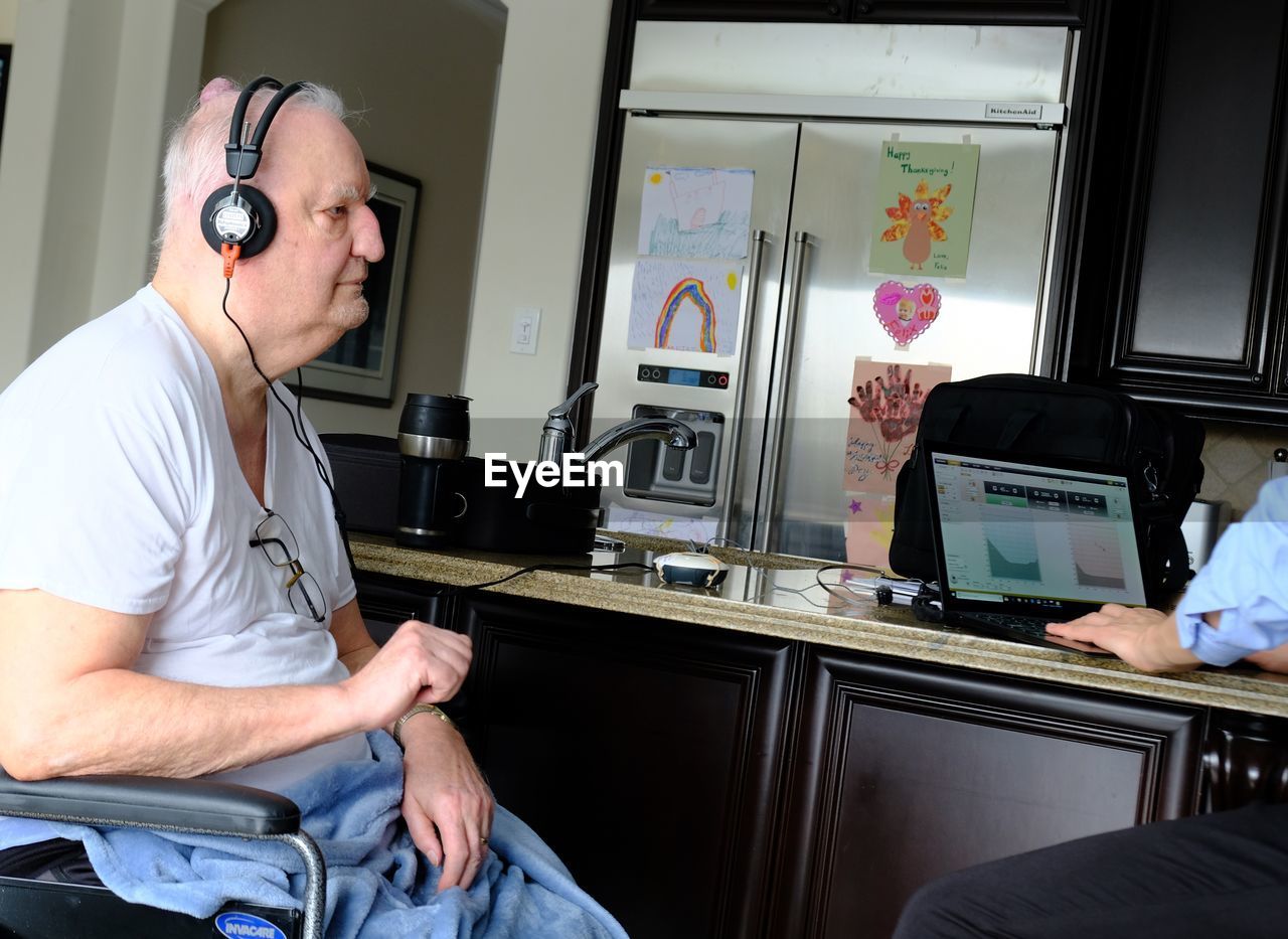 Senior male in wheelchair wearing headphones for hearing test