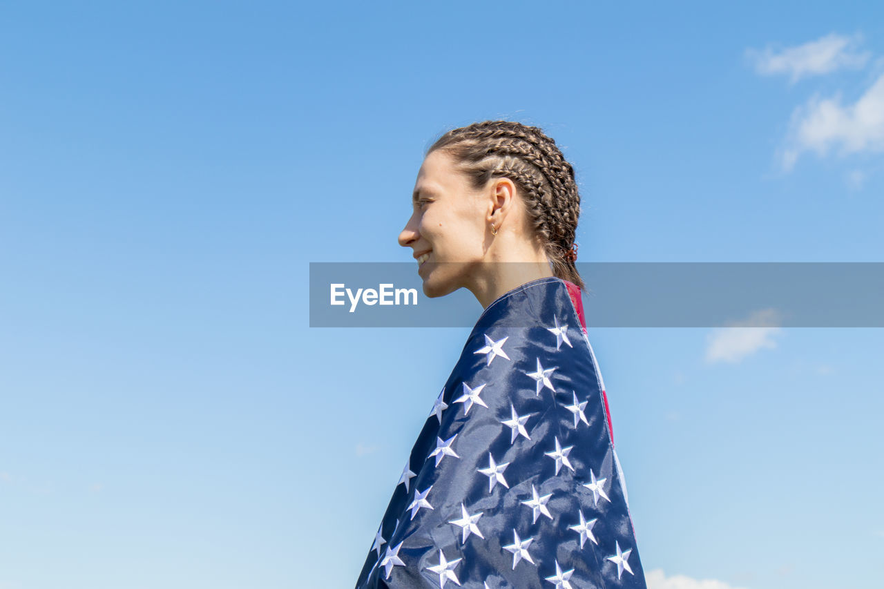 LOW ANGLE VIEW OF WOMAN LOOKING AT BLUE SKY