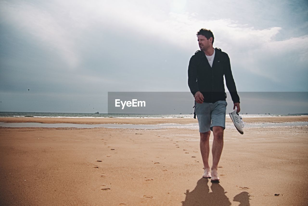 FULL LENGTH OF A MAN STANDING ON BEACH