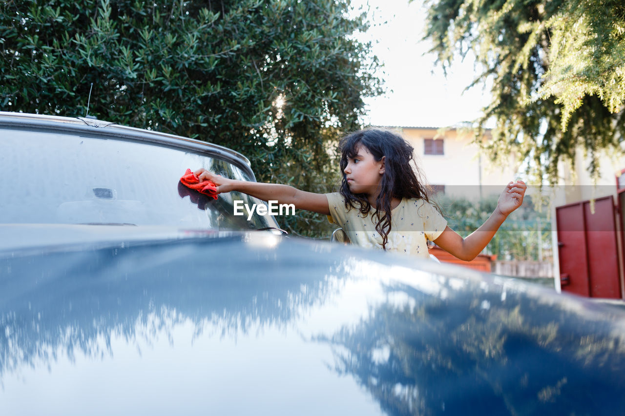 Girl washing blue car in the garden