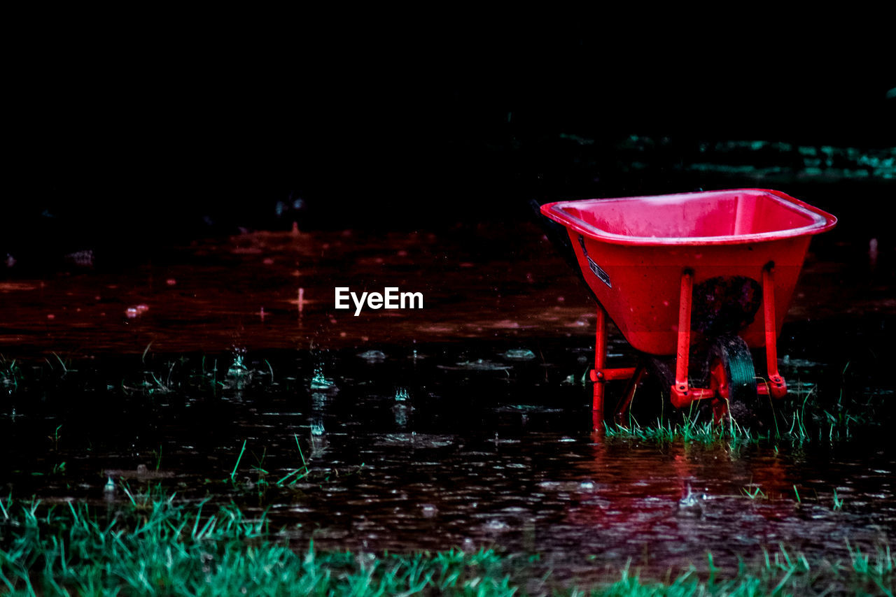 Red wheelbarrow on wet land during rainy season