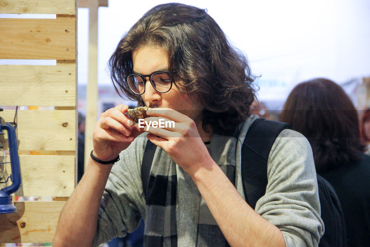 Young man eating while sitting at cafe