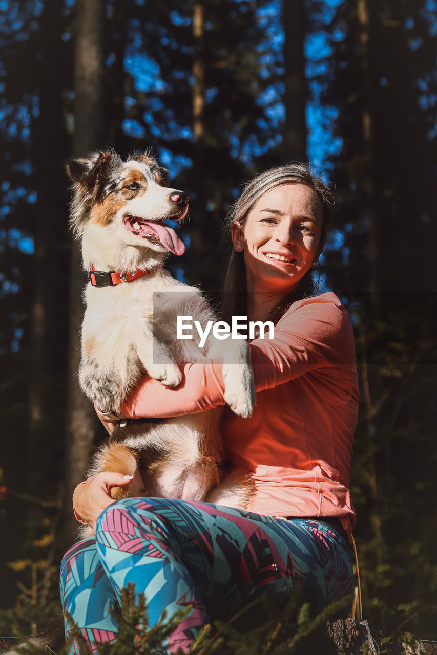 Candid portrait of a female athlete with her running and hiking partner, an australian shepherd dog