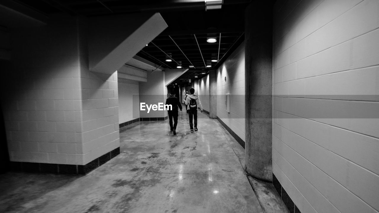 PEOPLE WALKING IN CORRIDOR OF ILLUMINATED BUILDING