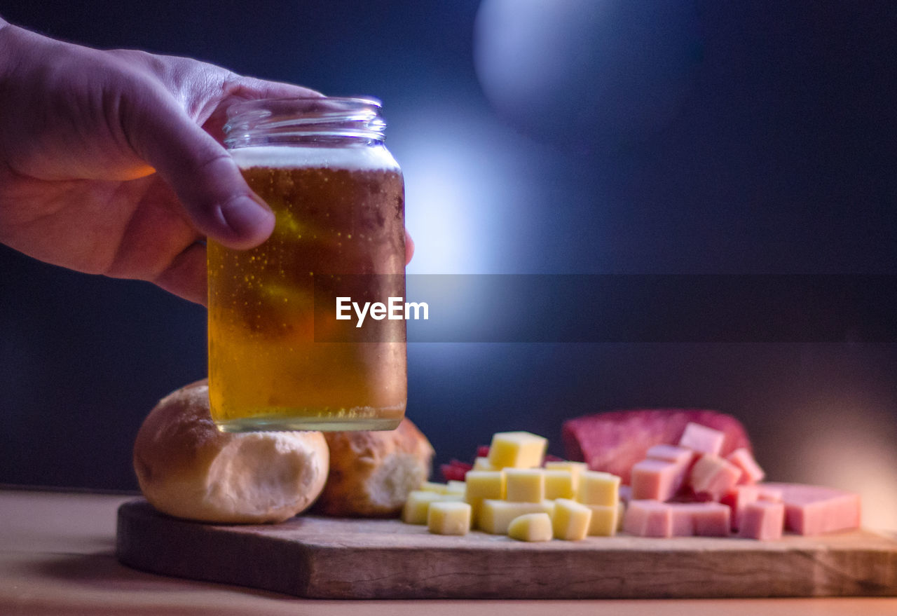 Cropped hand having beer with food at table