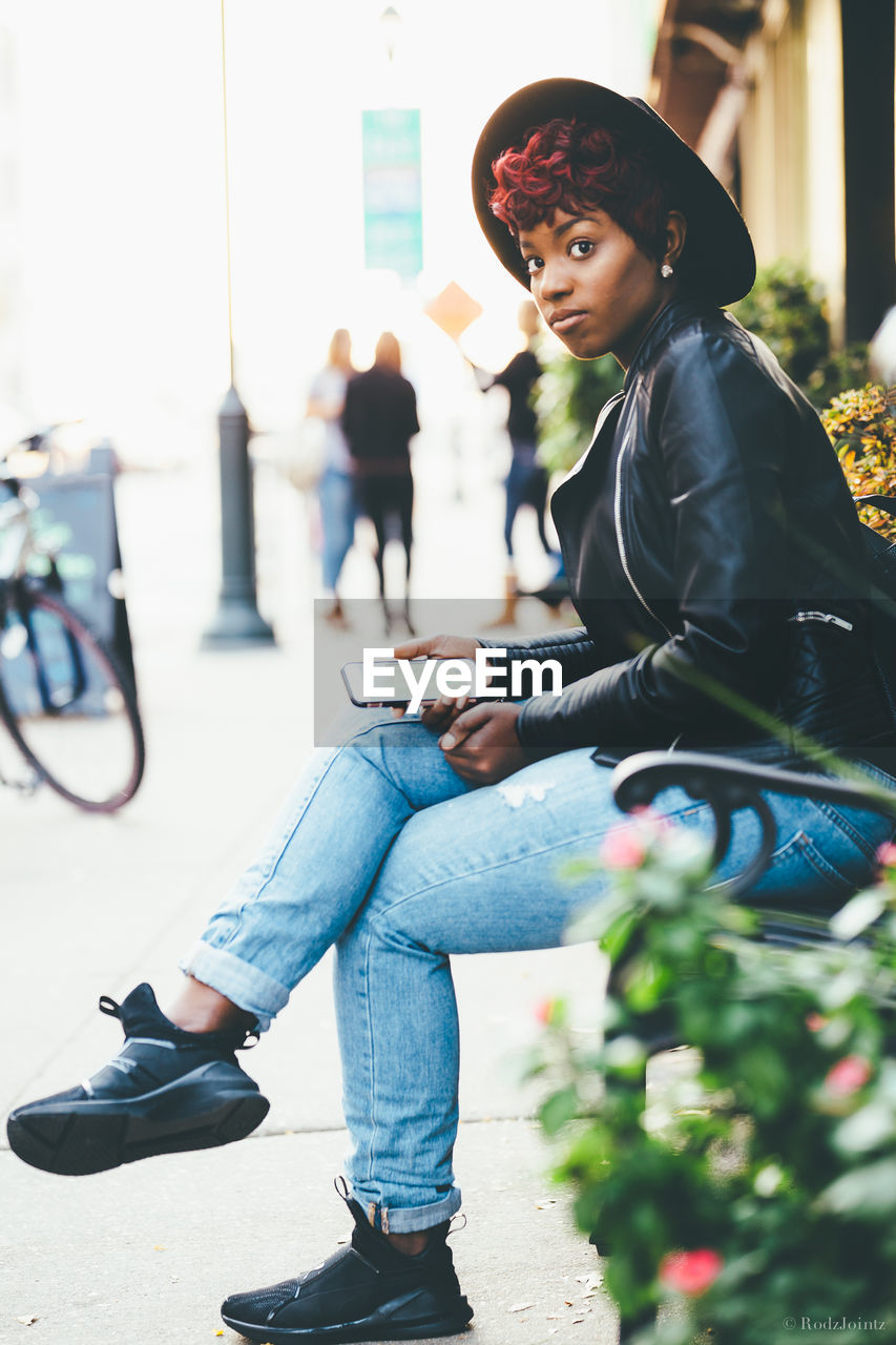 Portrait of young woman sitting on park bench