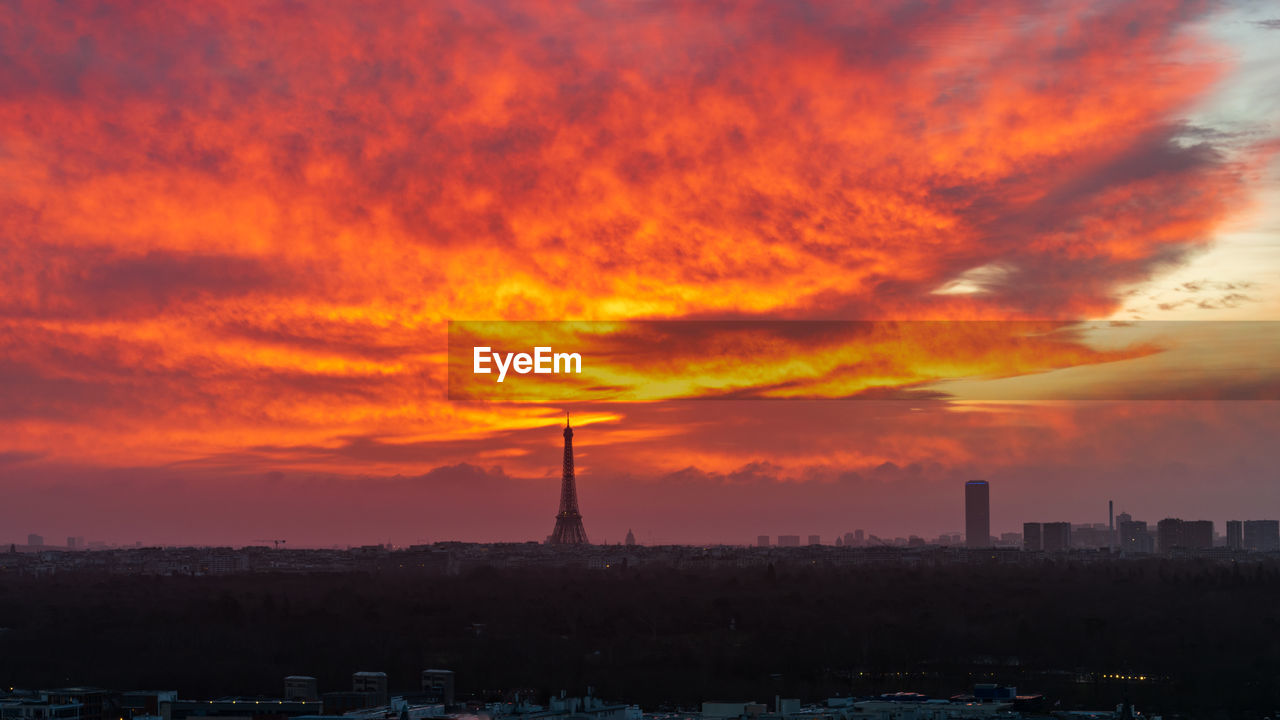 Silhouette eiffel tower against cloudy sky at sunset