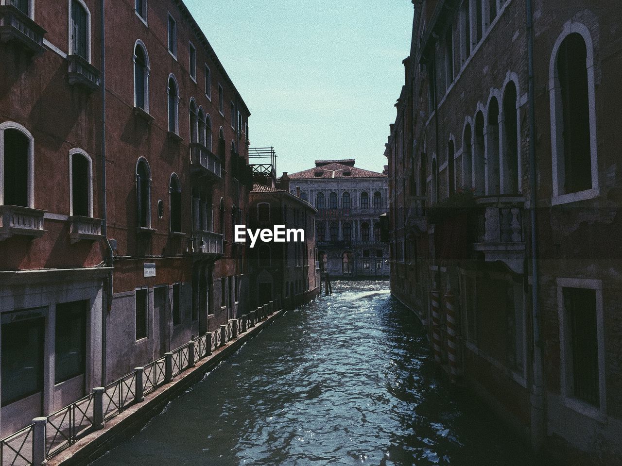 Canal amidst buildings against clear sky