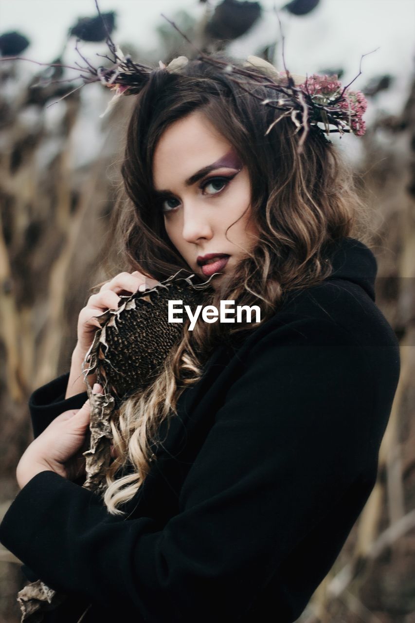 Side view portrait of beautiful woman holding dried sunflower